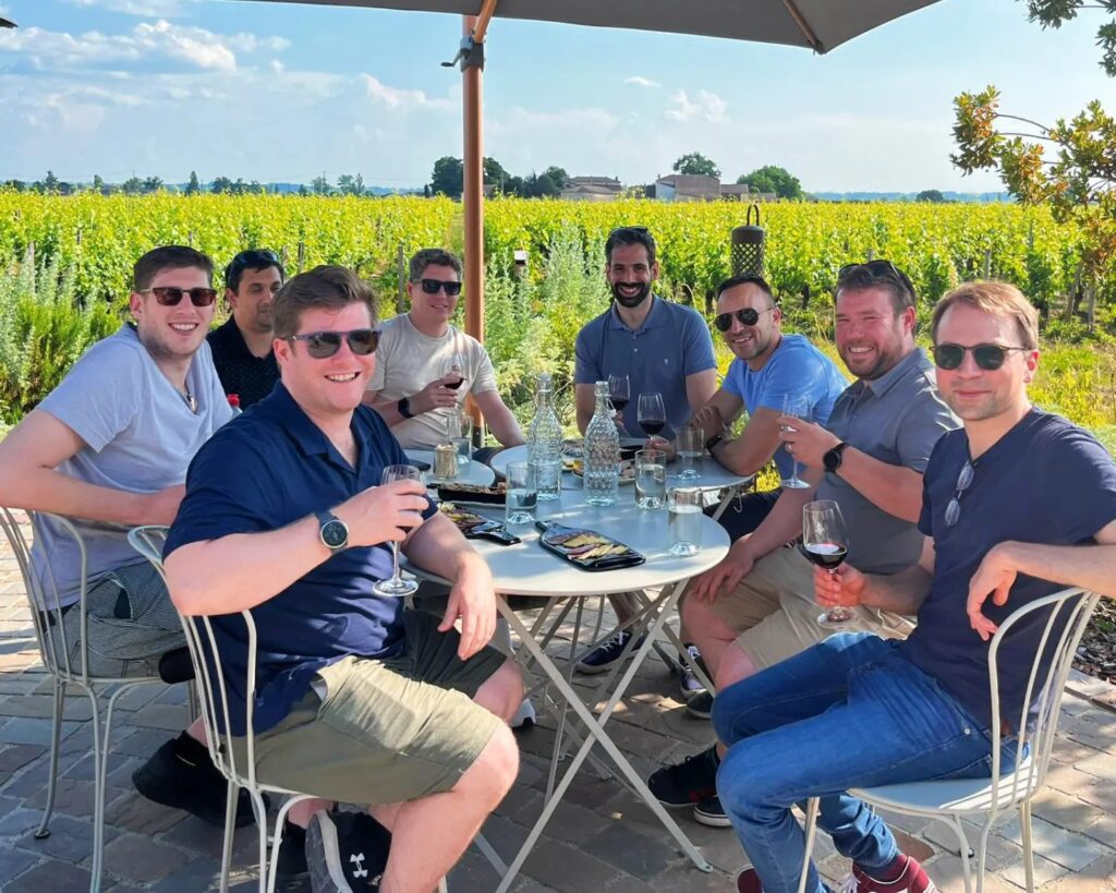 A group of lads drinking wine near a vineyard